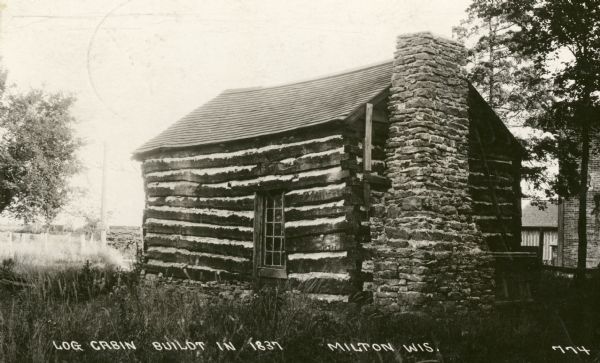A view of the cabin on the property of the Milton House, which was a part of the Underground Railroad prior to the abolition of slavery. The house was built in 1845 by Joseph Goodrich and turned into an Inn. The frame house and log cabin behind the Inn were also built by Goodrich, along with the Milton House Tavern. The Milton House was later taken over and turned into a museum. Caption reads: "Log Cabin Built in 1837, Milton, Wis."