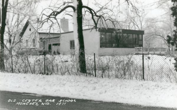 View from road across fence towards the Old Center Oak School in Monches. Snow is on the ground. Caption reads: "Old Center Oak School, Monches, Wis."