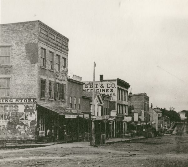 View down a cluttered Monroe street. The corner building later became Schuetze's Clothing Store.