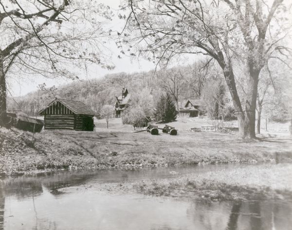 Buildings at "Little Norway."  From left to right: tool house, Norway house, Haugen homestead.  The wagon in foreground is a kubberulle; the wheels are sections of log bound with iron strips.