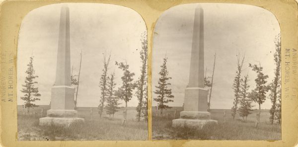 Stereograph of monument. This 17.5 foot granite monument was erected on September 15, 1901, to mark the location of a Norwegian Lutheran cemetery in the northwest quarter of the northwest quarter of Section 8.  Use of the cemetery began in 1847 and was discontinued in 1863 in favor of a new cemetery adjoining the Springdale Lutheran Church one mile to the southeast. The fifty or so burials had been marked with wooden crosses, but due to their later deterioration, a freewill subscription, begun in 1898, raised funds for a more permanent monument on which were inscribed the names of many of those buried there.