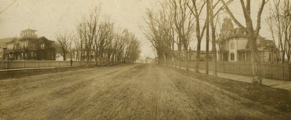E.S. Minorhouse on the right, Weston-Babcock house on the left. A person is standing on the sidewalk on the left in front of the Weston-Babcock House.