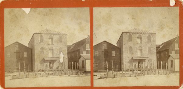 Stereograph of Island City Mill. Island City Mill was built in 1867 by Carl Stridde and A.H.F. Krueger, and also called Stridde & Krueger Mill. By 1891 it was known as Krueger & Lachmann Milling Co. (Stridde died in 1877.) Later the site was sold to the Kimberly-Clark Co. Two men are standing in the doorway.