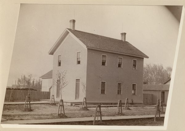 Exterior view of Second Ward School. Newly planted trees with wood supports are in the yard surrounding the school.