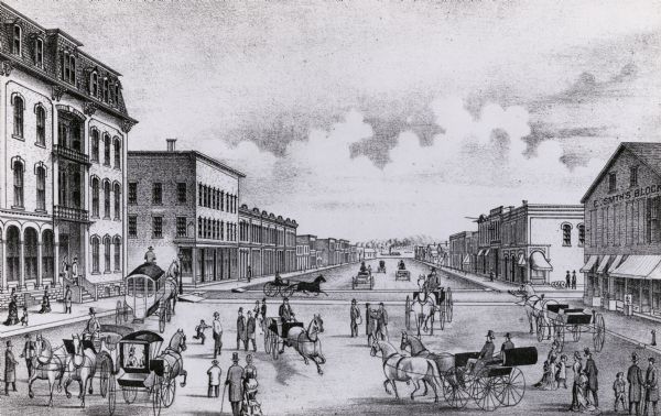 View of street. People walking and riding on horse and buggies. One building reads "E. SMTH'S BLOCK".