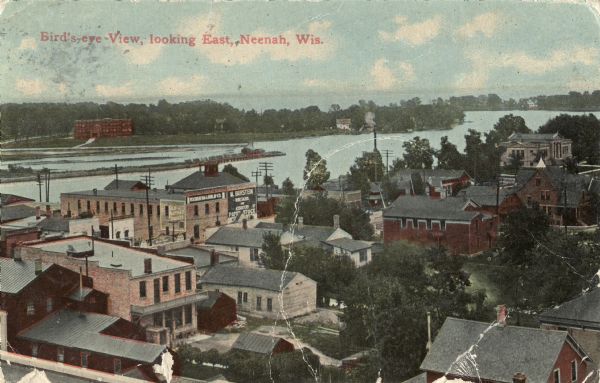 Elevated view over town towards the lake. Signs on some of the buildings read: "Old Partner Tobacco"; "Wisconsin Bag & Burlap Co."; "M. Burstein [?] and Associates Paper Stock". Caption reads: "Bird's-eye-View, looking East, Neenah, Wis."