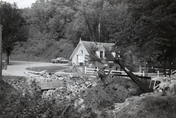 Nelson Dewey State Park (Cassville vicinity). Bridge construction near the park office which was built in the 1850s as a chicken house. The park was established out of the former estate (originally known as "Stonefield") of Wisconsin's first governor, Nelson Dewey. Car parked in lot next to office and woman sitting in front of office.