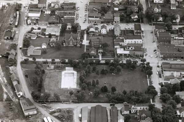 Aerial view of downtown, including park, church, and stores.