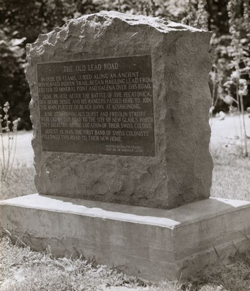 Old Lead Road Marker. Marker reads: "The Old Lead Road. In 1828, ox-teams, guided along an ancient Winnebago Indian Trail, began hauling over this road. June 29, 1832, after the battle of the Pecatonica, Gen. Henry Dodge and his Rangers passed here to join the main persuit of Black Hawk at Koshkonong. June 27, 1845, Niklaus Durst and Fridolin Streiff were led by this road to the site of New Glarus which they selected as the location of their Swiss colony. August 15, 1845, the first band of Swiss colonists followed this road to their new home.  Erected by Walter Stuessy, Post No. 141, American Legion".