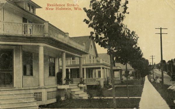 View down sidewalk of houses along the street. Caption reads: "Residence Street, New Holstein, Wis."