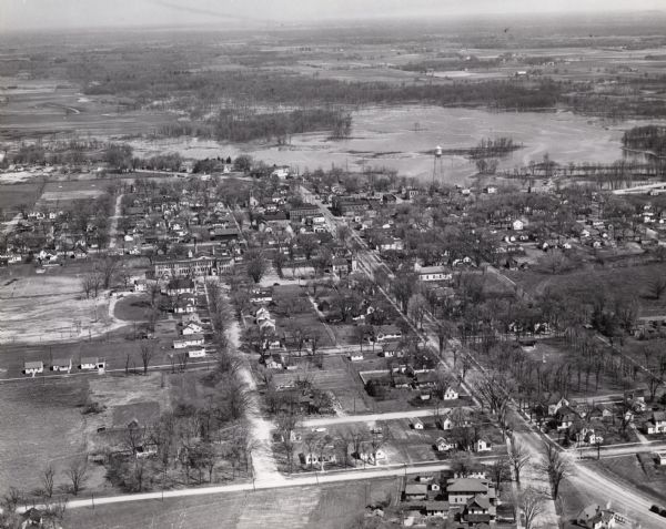 Aerial view of town including water tower, city streets, houses, and other buildings.