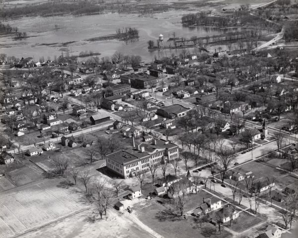 Aerial view of town including houses, water tower, city streets and buildings.