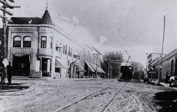 Main Street, south. View includes cable car on track, businesses, a post office, and five people standing on the sidewalks lining street.