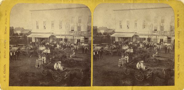 Stereograph of New Richmond(?) during a fourth of July celebration. Identification has not been fully verified, but there was a Coombs Hotel in this town at this time; and other factors also support this identification. Includes horse-drawn carts, crowds of men, women, and children, and two businesses (one with sign reading "Avery & Son" and the other, "Coombs Hotel").