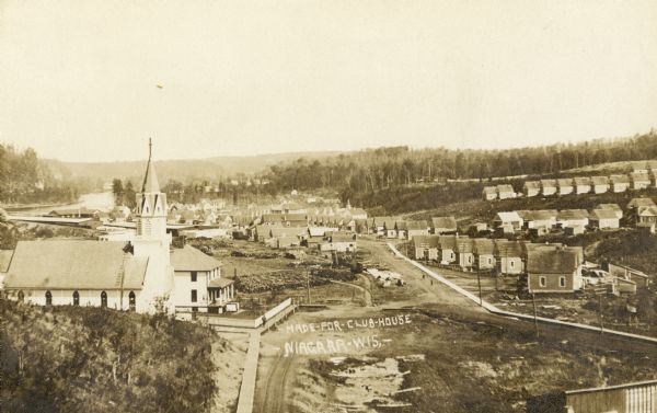An elevated view of town. A church is on the left, houses are in rows on the right. Caption reads: "Made-For-Club-House — Niagara-Wis.—".
