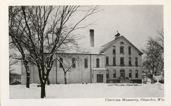 View across snow-covered ground towards the buildings of the Cistercian Monastery. Caption reads: "Cistercian Monastery, Okauchee, Wis."