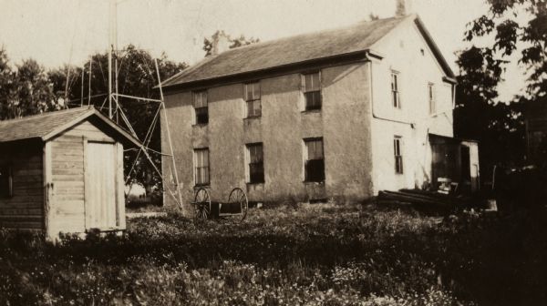 Clausen farmhouse, the residence of C.L. Clausen. The base of a windmill is on the left behind a small outbuilding.