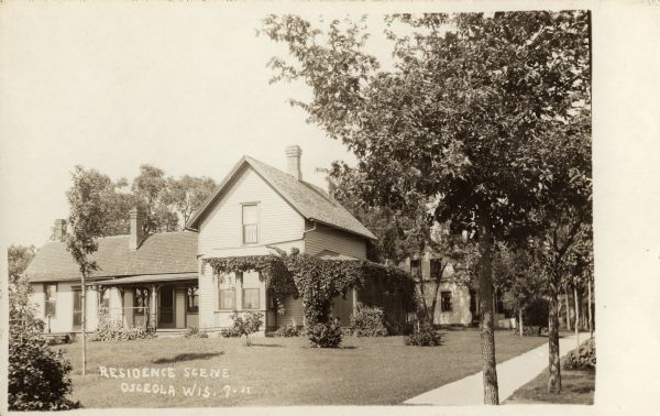 View across yard towards a residence. Caption reads: "Residence Scene Osceola, Wis."