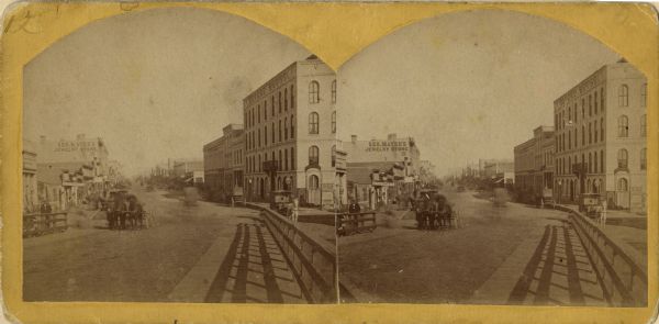 Stereograph of Main Street viewed from the bridge. The Revere House is just beyond the bridge on the right, and on the left is a sign on the side of a building that reads: "Geo. Mayer's Jewelry Store. 15".