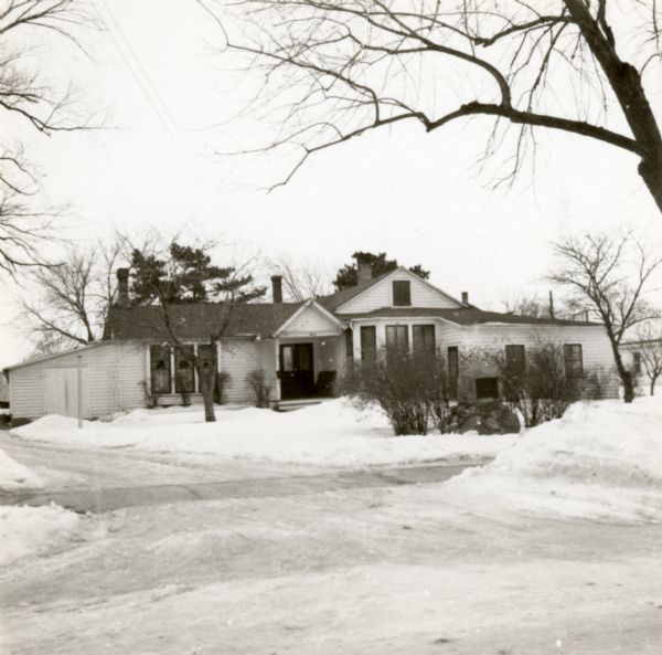 View from street towards the residence of J.H. Osborn. Snow is on the ground. Osborn moved to Oshkosh permanently in 1844 from New York City. He farmed, traded real estate, and was involved in local politics.