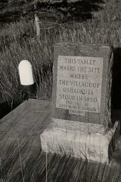 A marker at the site of the former village of Oshaukuta on Highway 51, north of Portage. The marker states: "This tablet marks the site where the village of Oshaukuta stood in 1850. Erected by Levi W. Hutchinson in 1940."