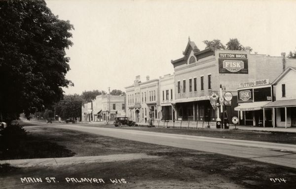 View looking across Main Street. On the right, Tutton Bros. repair shop and service station can be seen. Caption reads: "Main St. Palmyra Wis."