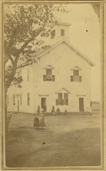 The first high school erected in Palmyra, built about 1860. People are standing in the yard.