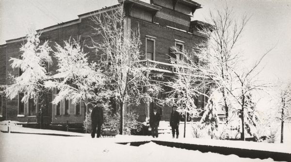 A view of the Park Hotel in winter. A man on the left is pulling a sled piled with firewood.