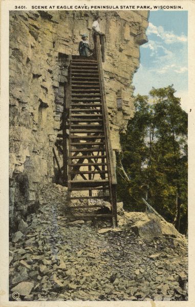 View of the steps leading to Eagle Cave on Eagle Bluff. The bluff received its name from the eagles which formerly nested there. Caption reads: "Scene at Eagle Cave; Peninsula State Park, Wisconsin."