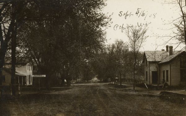 View down a main dirt road in Pepin. To the left is a sign for a livery stable.