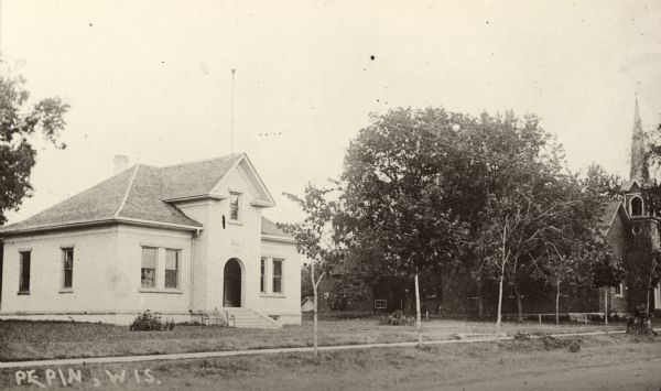 View from road of the Pepin Village Hall. The Methodist Church is at the far right. Caption reads: "Pepin, Wis."