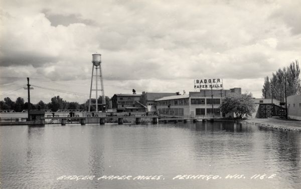 View across water towards the Badger Paper Mills, founded by E.A. Meyer. Caption reads: "Badger Paper Mills, Peshtigo, Wis."