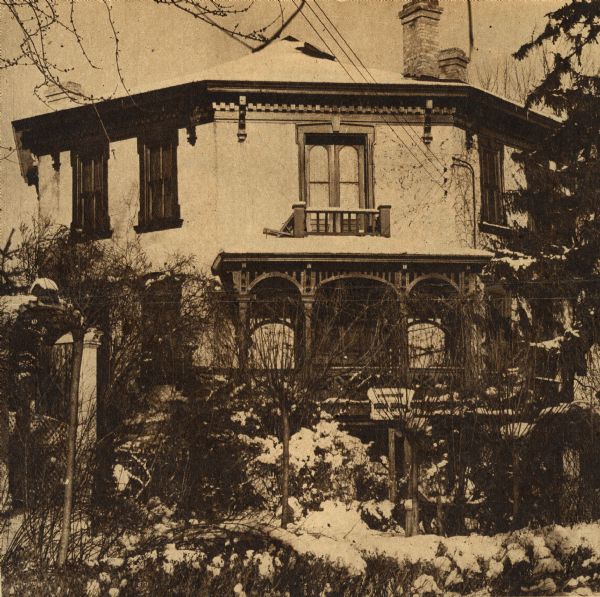 Exterior of Octagon House. The caption reads: "The Pewaukee octagon house is the one for Poe. Legend says the man who built it killed his wife. Truth explains the mysterious noises that were heard in the walls. When it was built, intercommunication speaking tubes were placed in the walls. With time, the outlets were covered with wall paper but still transmitted sounds."