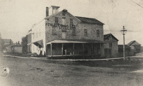 View of Pewaukee Lake Mills. Asa Clark, a Vermont pioneer who settled in the town of Pewaukee in 1837, erected a sawmill in 1838 at the outlet of the lake. In 1845 he erected a three-story stone flour mill. In 1854, Benjamin Boorman bought it and later enlarged it. At one time his sons ran a cracker factory in conjunction with the mill. After standing empty for many years it was razed in 1927.