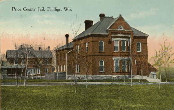View across lawn towards the Price County Jail. Caption reads: "Price County Jail Phillips, Wis."