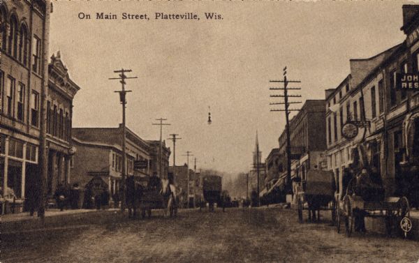 View looking down center of Main Street, with horse-drawn vehicles. Caption reads: "On Main Street, Platteville, Wis."