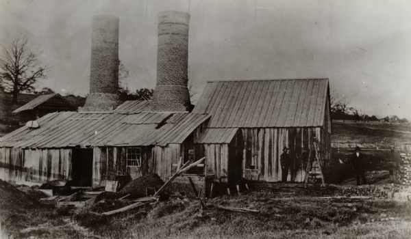 A straw lead furnace, an open hearth furnace where lead sulphite (Galena) was roasted. Located on the Rountree branch of the Little Platte River, Richard Straw and Co. were owners and operators. Shown here are John Johnson, Richard Straw, and William Pedelty.