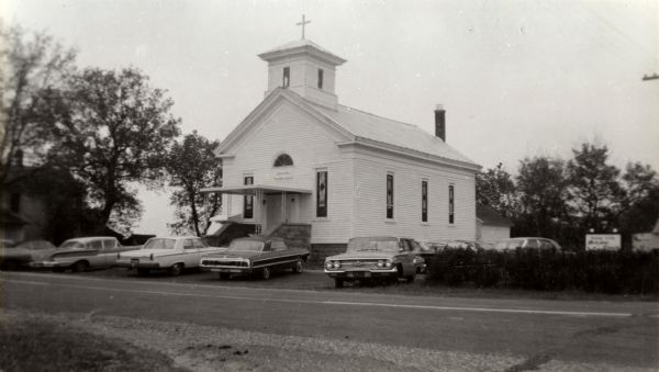 View across road towards the Buena Vista United Methodist Church. A row of cars are parked in front.