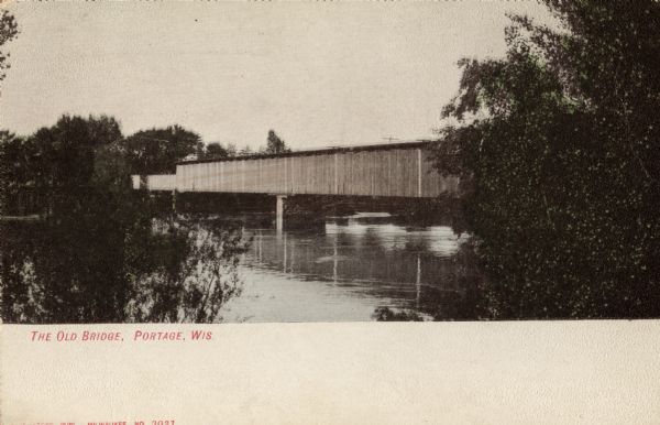 Covered bridge over river. Caption reads: "The Old Bridge, Portage, Wis."
