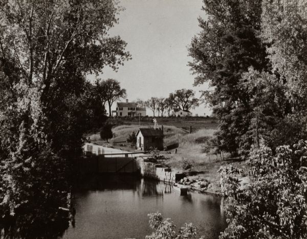 Elevated view of the Indian Agency House near the site of Fort Winnebago. View of Portage Canal in foreground. The canal was dug in 1849 as part of the Fox-Wisconsin waterway project.