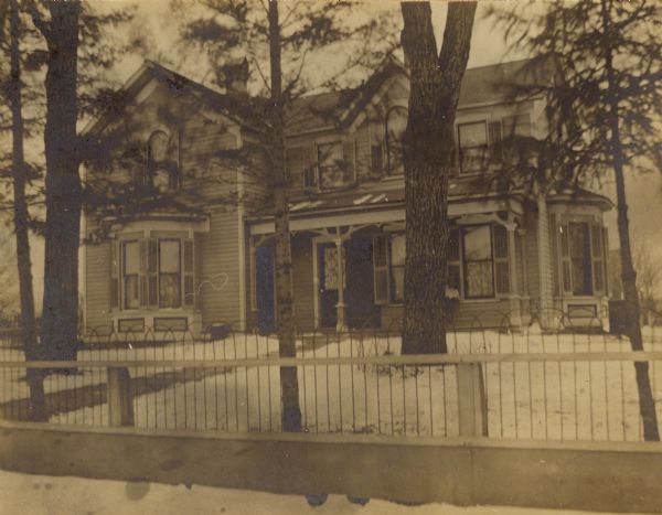 Elijah Hinkson residence, with a fence in the foreground. Snow is on the ground.
