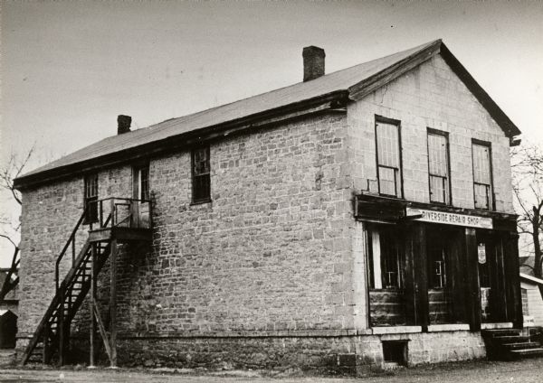 Former building of the Astor Company, also known as the Brisbois Fur Trading Post. At the time this image was made, the structure was occupied by Ben Schaub's Riverside Repair Shop.