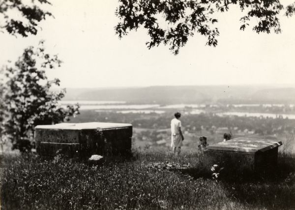 Brisbois grave, tomb of Michael Brisbois. A woman is standing behind the graves, looking out to Prairie du Chien and the Mississippi River.