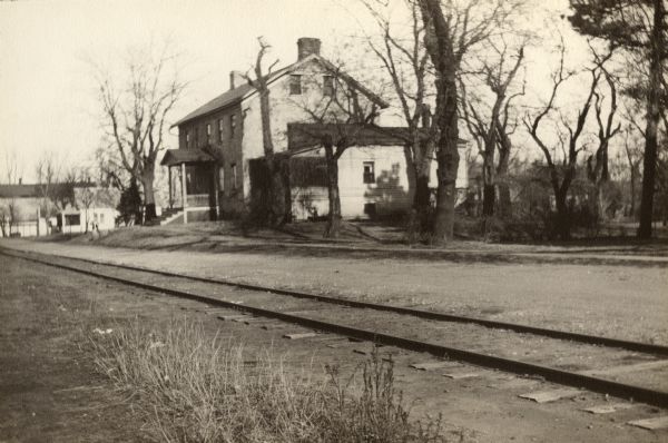 View across railroad tracks towards the Brisbois House.