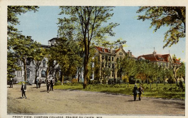 People in the foreground are walking on a road. College buildings are in the background behind trees. Caption reads: "Front View, Campion College, Prairie du Chien, Wis."