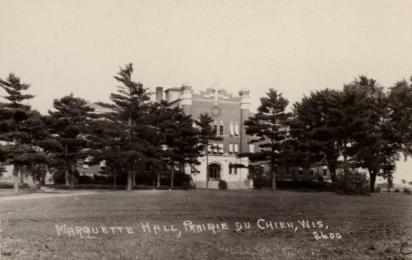 View across grounds towards Marquette Hall, a dormitory at Campion College. Caption at bottom reads: "Marquette Hall, Prairie du Chien, Wis."