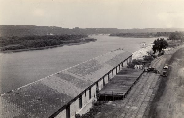 Elevated view over the long roof of the Diamond Jo warehouse. The Mississippi River is on the left, with hills in the background.