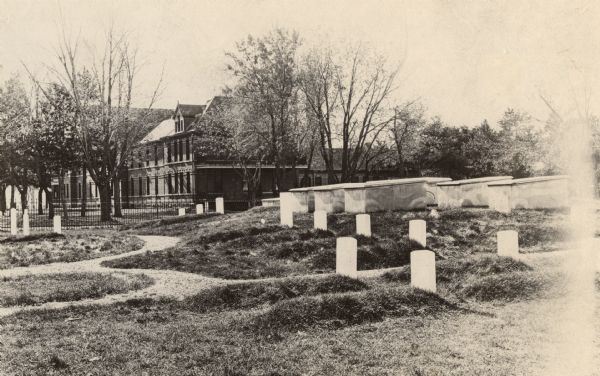 Fort Crawford Military Cemetery, after restoration by the United States Government. In the left background is the Prairie du Chien Sanitarium, built on the John Lawler homestead, part of the Fort Crawford reservation.