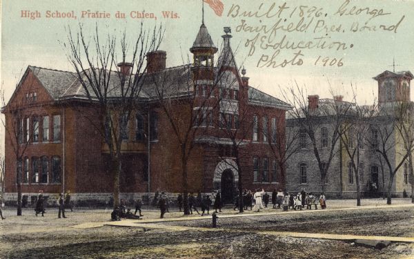 View of the high school, with children are playing in the school yard. Caption reads: "High School, Prairie du Chien, Wis."