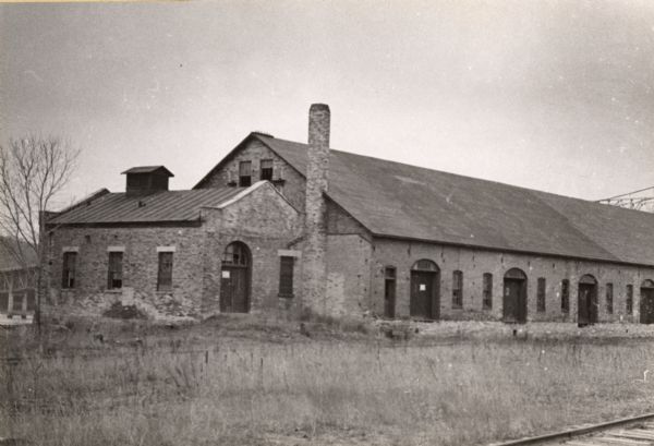 Exterior of warehouse, which was formerly a five story grain elevator. This building stood downstream from the Diamond Jo warehouse. A section of the Mississippi River bridge can be seen in the background on the right just above the roof of the warehouse. Railroad tracks are in the right foreground.